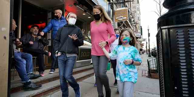 Menschen, die die Straße entlang gehen, tragen Masken gegen COVID-19.