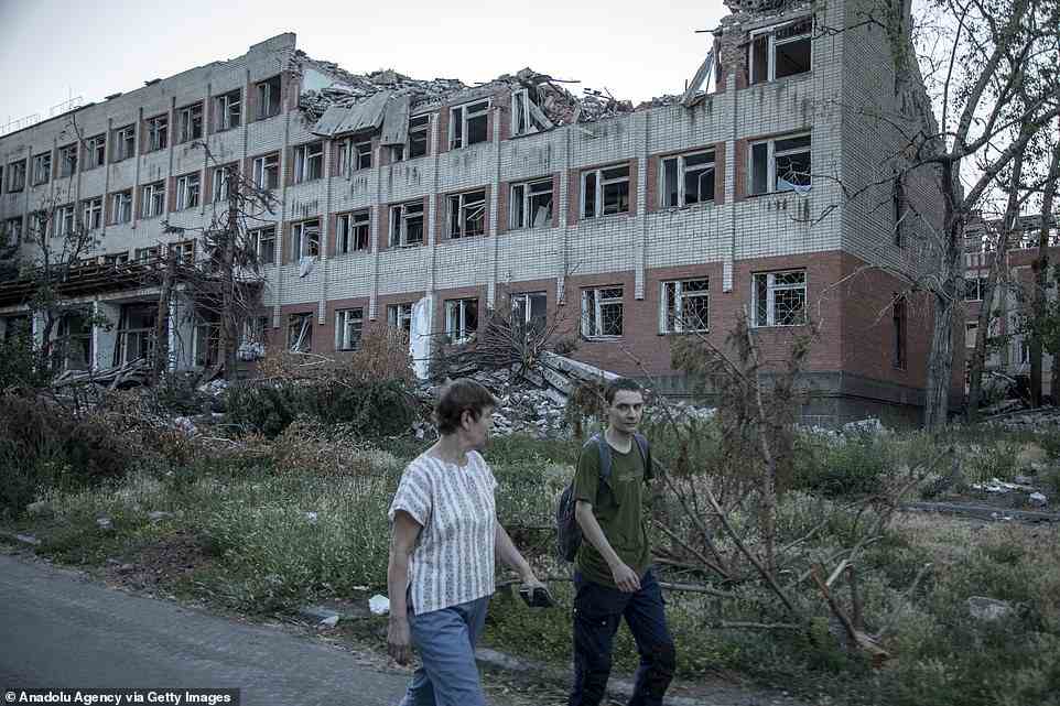 Nina Zakharova, 64-years-old librarian, and her son Alexander, 26 years-old, walk nearby a university building targeted by a missile strike in Bakhmut