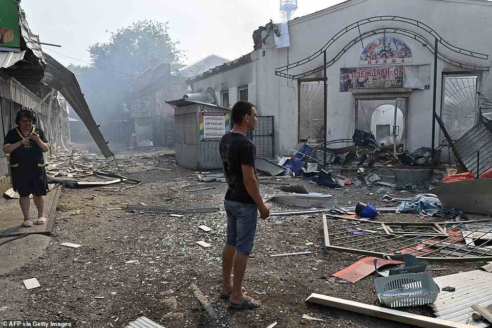 Local residents look at destroyed shops on a local market after a rocket attack in the Ukrainian town of Sloviansk