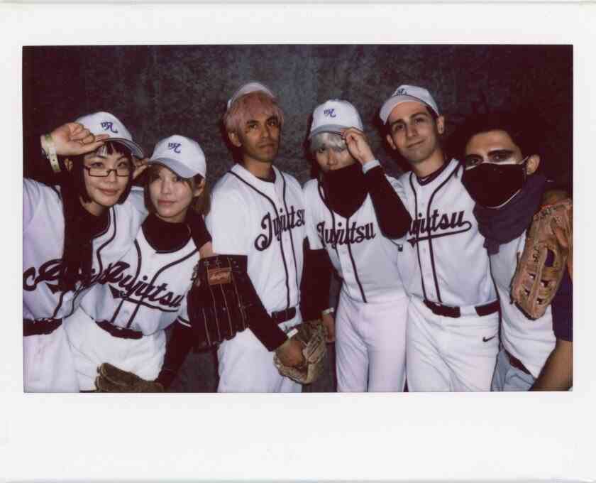 Sechs Männer und Frauen, die Baseballuniformen mit dem Wort tragen "Jujutsu" auf der Vorderseite geschrieben.