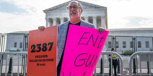 Ein Demonstrant hält am 8. Juni 2022 vor dem Obersten Gerichtshof in Washington, DC Schilder, die ein Ende der Waffengewalt fordern.  Das Gericht wird voraussichtlich diesen Monat eine Reihe hochkarätiger Entscheidungen bekannt geben.  