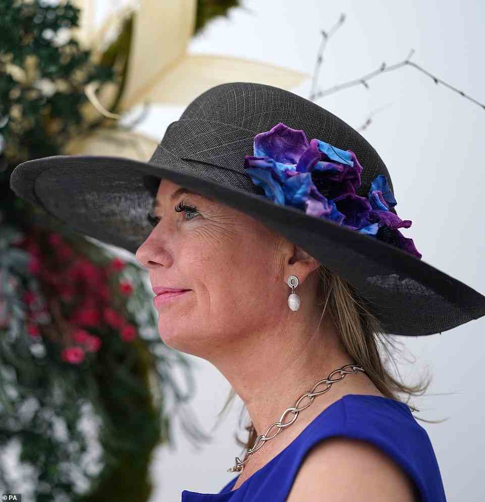One fashionable racegoer opted for a muted black headpiece for Ladies Day - but added a pop of colour with a vibrant blue and purple floral addition