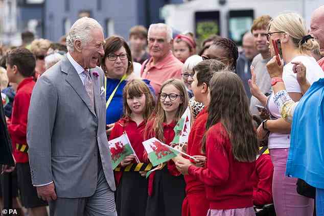 Schoolchildren waving the Welsh flag and their parents enthusiastically welcomed Charles to their town