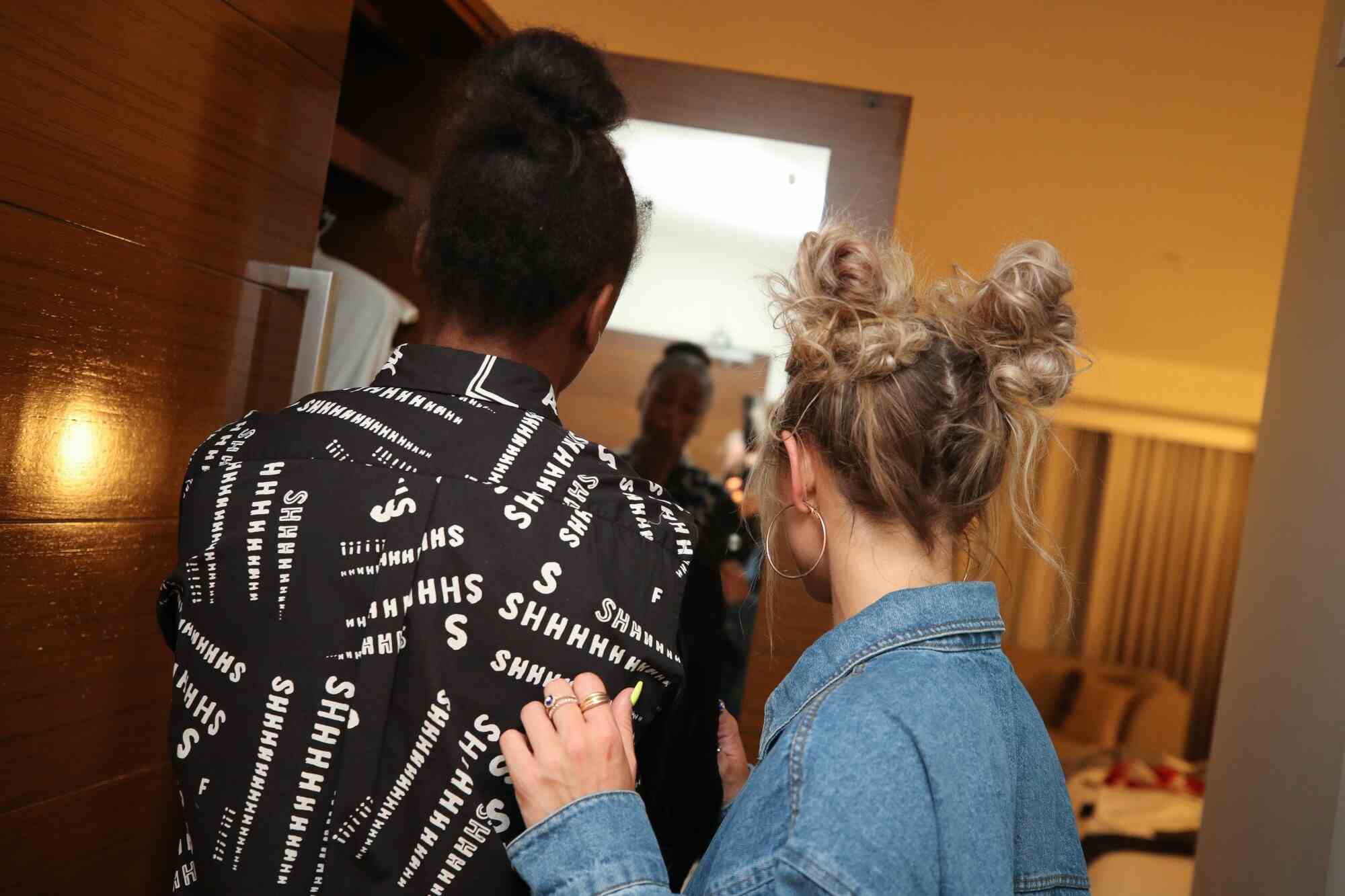 Jewell Loyd und Stylistin Sydney Bordonaro begutachten ein Hemd im Spiegel.