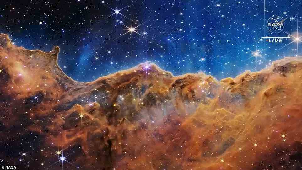 At the bottom of the image is the western section of NGC 3324, and what NASA calls the 'Cosmic Cliffs' – an orangey-brown landscape of 'craggy mountains' and 'valleys' speckled with glittering baby stars. NASA experts don't even know what some of the structures are in this image, because they are so unprecedented