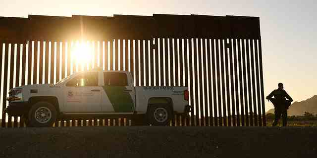 Ein Grenzschutzbeamter geht am 1. Juni 2022 in Yuma, Arizona, durch eine Lücke entlang der Grenzmauer zwischen den USA und Mexiko. 
