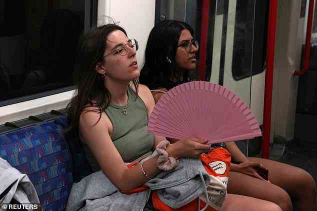 Eine Frau hält einen Fächer, während sie versucht, cool zu bleiben, während sie heute in der Londoner U-Bahn fährt.  Die Chefs von Transport for London fordern die Menschen auf, am Montag und Dienstag nach Möglichkeit nicht zu reisen