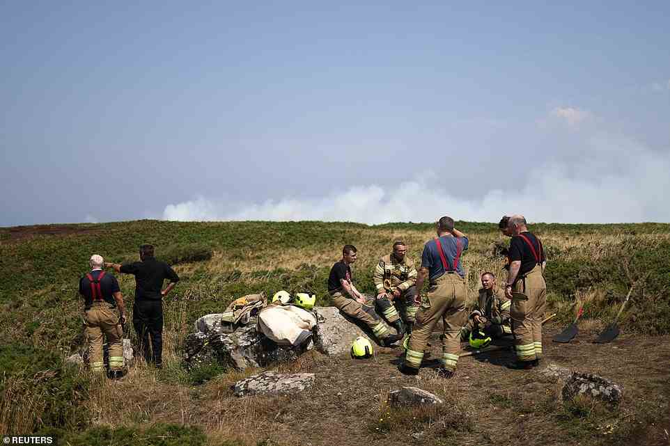 Firefighters rest as they attend a gorse bush fire during a heatwave near Zennor in Cornwall this afternoon