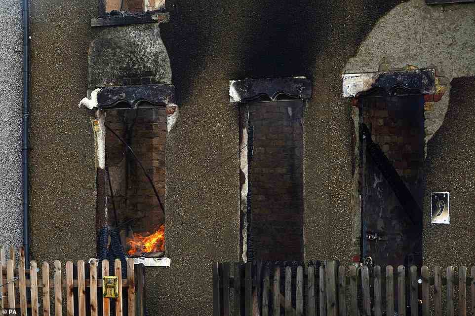 This picture shows the fire still burning at a home which has been blackened and its roof torn off amid devastating fires