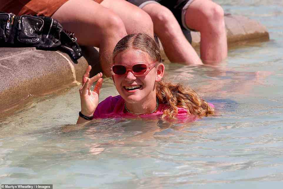 A young woman in the fountains at Trafalgar Square in London today as the heatwave continues