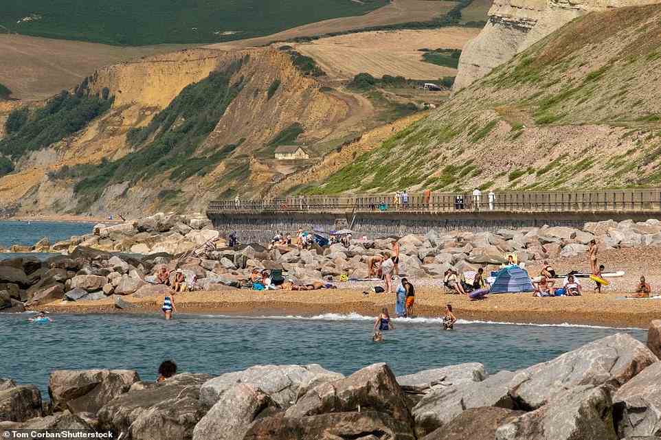 Beachgoers make the best of the scorching morning temperatures at West Bay in Dorset today