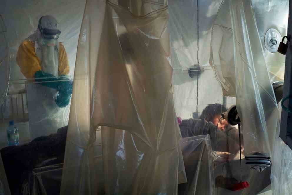 FOTO: Ein medizinisches Personal in Schutzausrüstung untersucht einen Patienten, der in einem Plastikwürfel in einem Ebola-Behandlungszentrum in Beni, Kongo, isoliert ist, 13. Juli 2019.