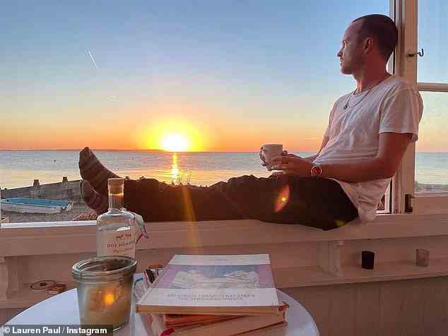 Entspannt: Ein anderes Bild zeigte Aaron, wie er auf die Aussicht auf den Strand blickte, während er sich auf einem Fenstersims zurücklehnte, um den Sonnenuntergang zu beobachten