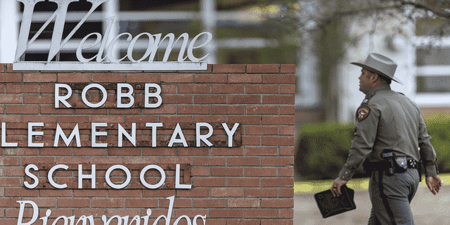 Ein State Trooper geht am Dienstag, den 24. Mai, am Schild der Robb Elementary School in Uvalde, Texas, vorbei.