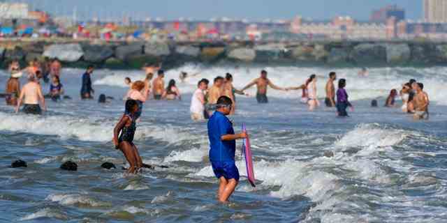 Die Menschen genießen das Wasser am Rockaway Beach, Dienstag, 19. Juli 2022, im New Yorker Stadtteil Queens. 