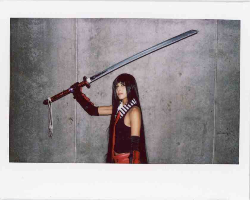 Eine Frau mit langem, glattem, dunklem Haar hält ein riesiges Schwert über ihrem Kopf.