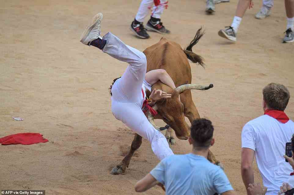 Ein Teilnehmer wird am Ende des Kurses von einem Stier in der Manege in die Luft gehoben, als Pamplonas berühmtes San-Fermin-Fest begann