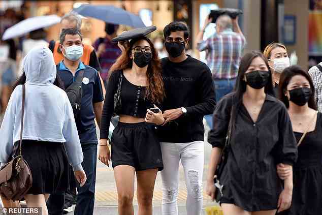 Shock data has revealed Covid case numbers in New Zealand and Singapore - where masks are reularly worn all the time outdoors, as seen here - have overtaken Australia in the latest Omicron wave despite ultra-strict mask mandates