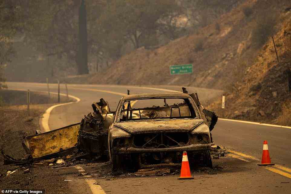 The charred remnants of a car towing a trailer that burned when fire jumped the Klamath River remain on the highway at the McKinney Fire in the Klamath National Forest northwest of Yreka, California