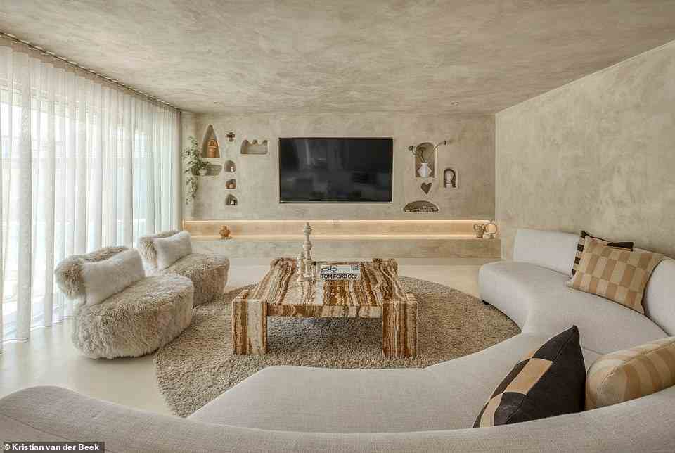 Das atemberaubende Wohnzimmer mit warmer, maßgefertigter Beleuchtung und mediterran beeinflussten, schrulligen Nischen, um Schmuckstücke zu präsentieren, macht Stein gemütlich