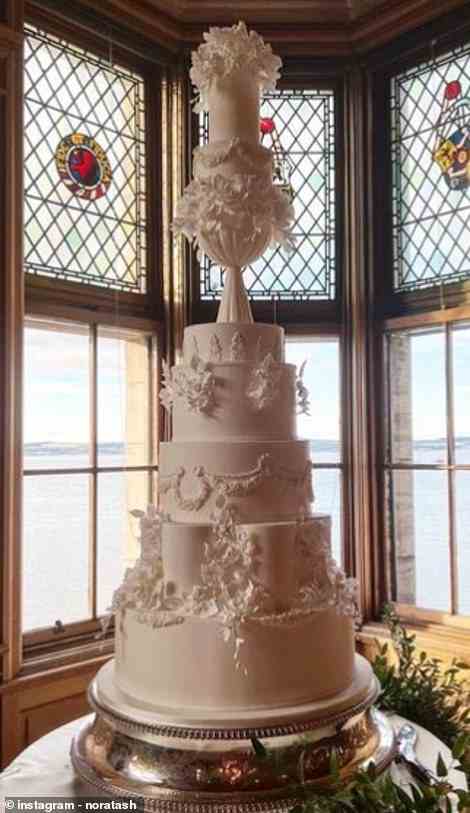 Die Torte, die vor einer Reihe von Fenstern mit Blick auf das Meer aufgestellt wurde, war mit feinem Zuckerguss geschmückt und hatte satte acht Ebenen
