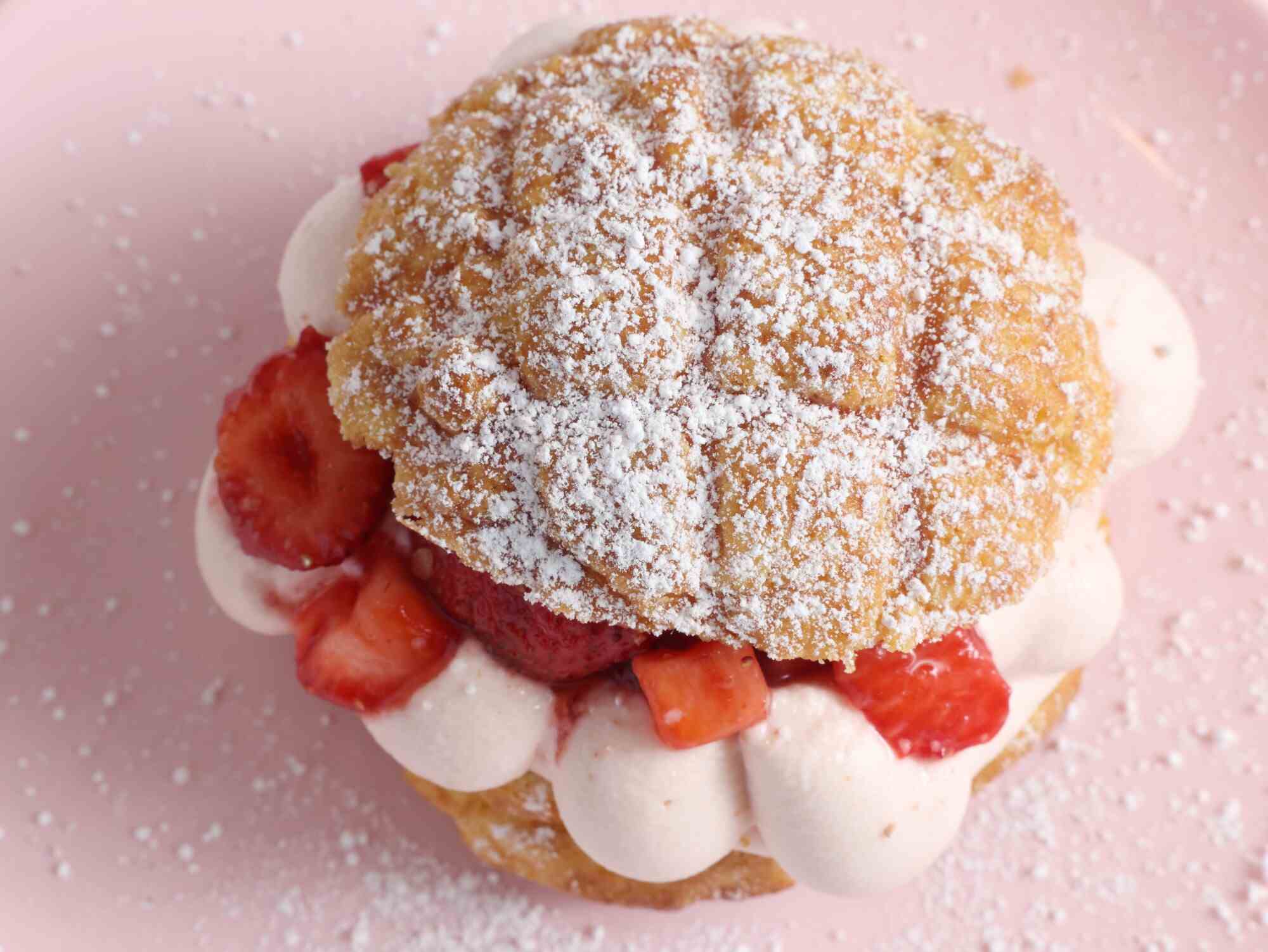Ein Erdbeer-Shortcake-Bolo sitzt auf einem rosa Teller.