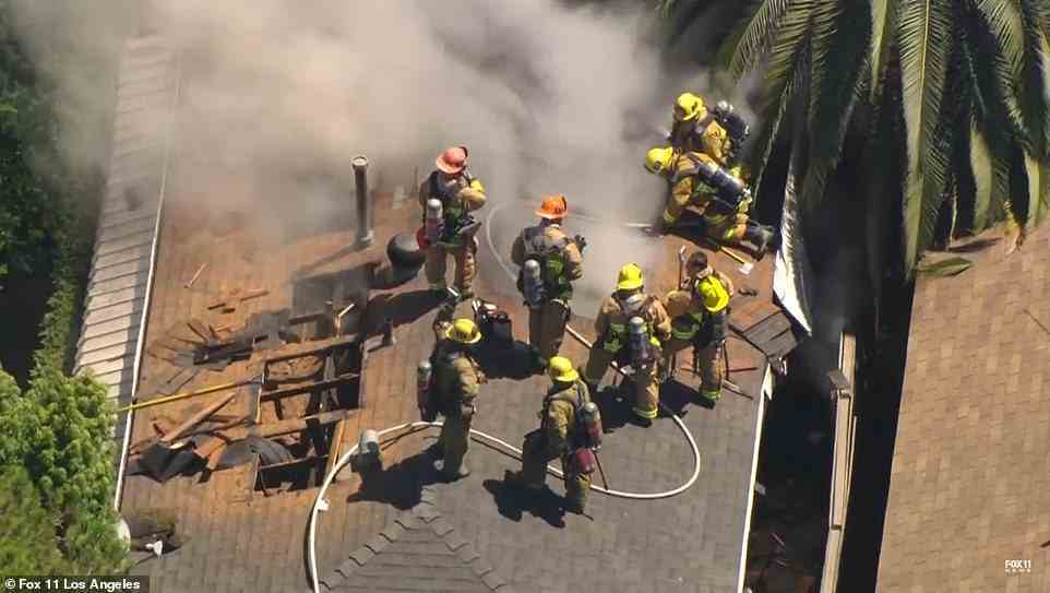 Smoke can be seen billowing out of the roof of the home which the LA Fire Department say has been destroyed