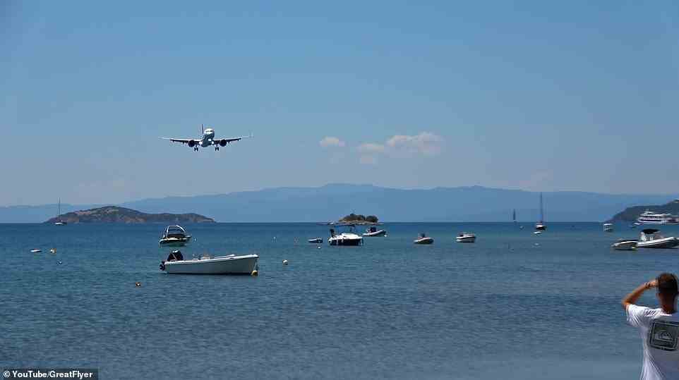 The video (pictured) opens by showing a plane in the distance cruising towards the Skiathos Alexandros Papadiamantis Airport over the turquoise waters of the Mediterranean