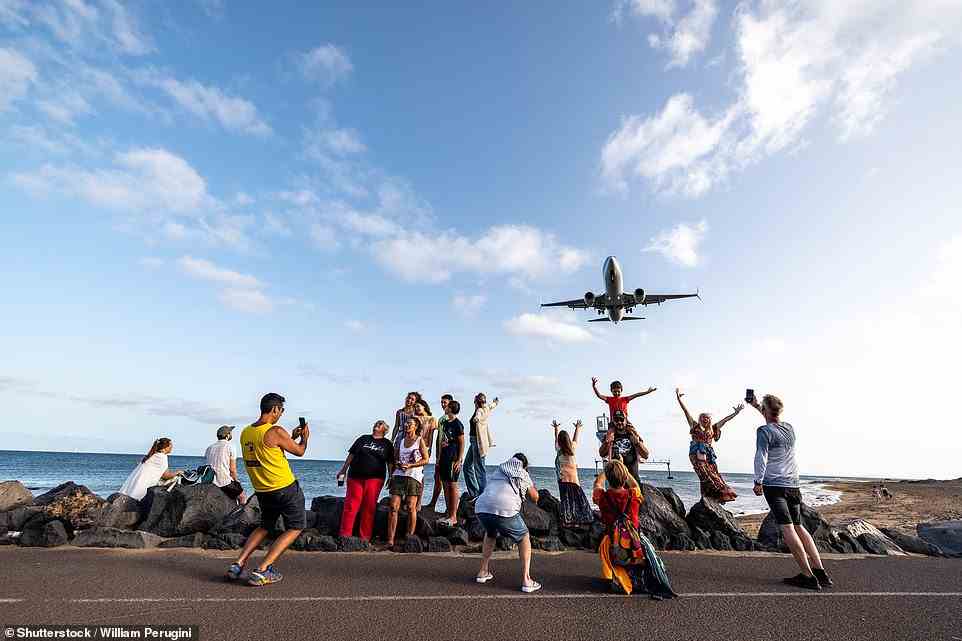 Pictured: People take selfies as a plane comes in to land at Arrecife airport on the Spanish island of Lanzarote, July 2022