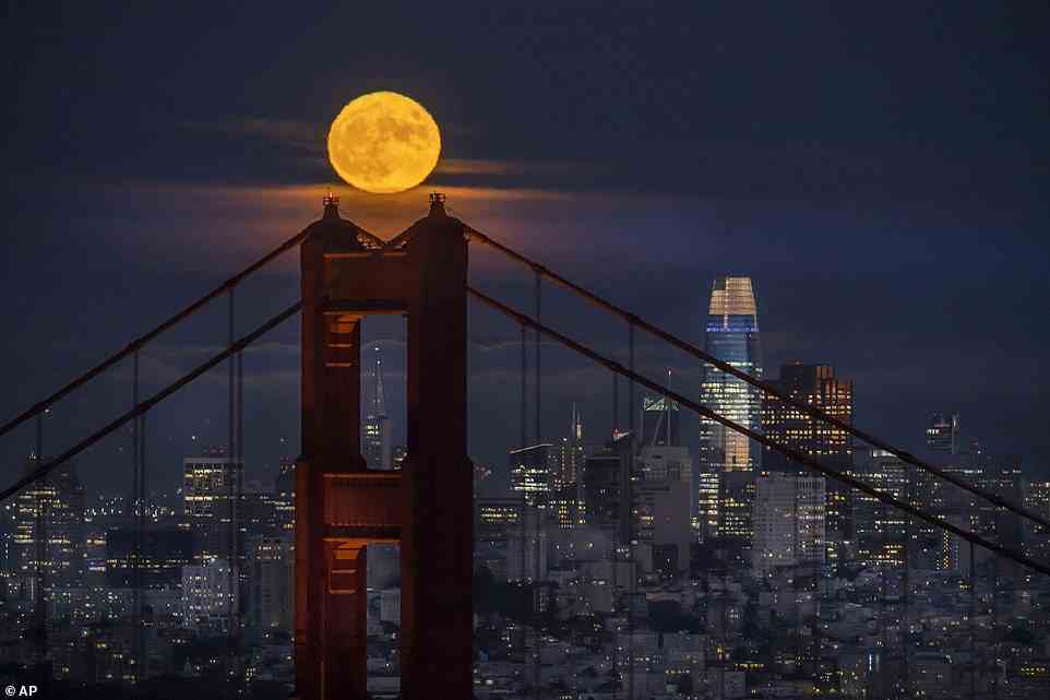 The supermoon rises above the Golden Gate Bridge and the San Francisco skyline as seen from Sausalito, California on Thursday