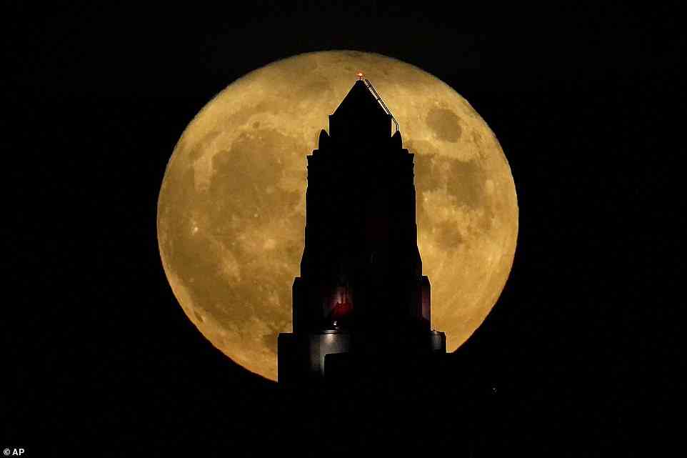 The stunning supermoon rises beyond the Art Deco spire of the Power and Light building in downtown Kansas City, Missouri