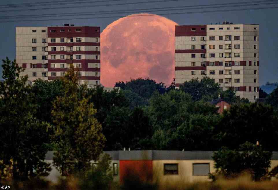 The full moon sets behind apartment houses in the outskirts of Frankfurt, Germany, in the early hours of Friday, Augus