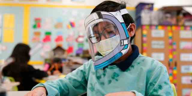 Ein Schüler trägt in einer vierten Klasse während der COVID-19-Pandemie an der Washington Elementary School am 12. Januar 2022 in Lynwood, Kalifornien, eine Maske und einen Gesichtsschutz. 