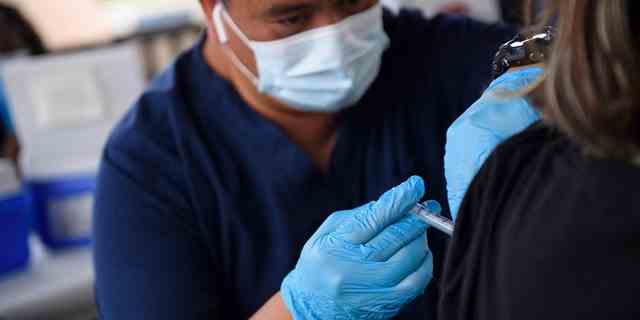 Eine Krankenschwester verabreicht einem Gymnasiasten während einer mobilen COVID-19-Impfklinik der City of Long Beach Public Health auf dem Campus der California State University Long Beach am 11. August 2021 in Long Beach, Kalifornien, eine Dosis des Pfizer-COVID-19-Impfstoffs . 