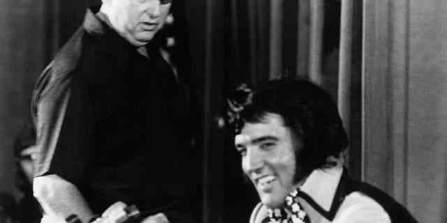 Elvis Presley wird gesehen, wie er später am Abend bei einer Pressekonferenz im Madison Square Garden Hof hält, um seine Show bekannt zu machen, während Colonel Tom Parker am 9. Juni 1972 im Hilton Hotel in New York City zuschaut.