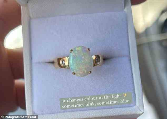 Der Opal ist in ein Goldband eingefasst und scheint von zwei weiteren Edelsteinen flankiert zu werden