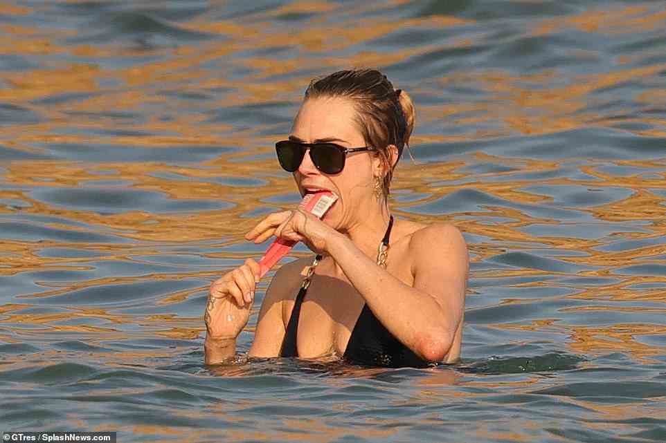 Tasty! Making the most of the fine weather, Cara was seen devouring a Calippo ice lolly, even bringing the sweet treat into the sea with her