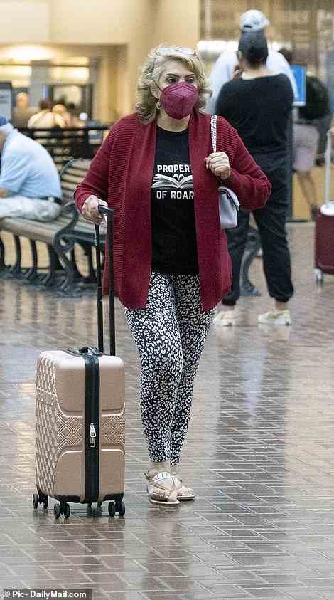 Her mother was seen at the airport in a red cardigan and sandals, pulling a small pink suitcase