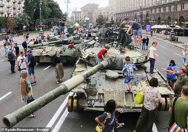 Eine Gruppe von Kindern klettert heute auf einen zerstörten russischen Panzer im Zentrum von Kiew