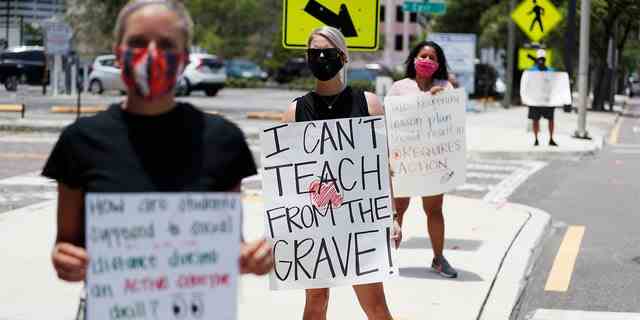 Die Mittelschullehrerin Brittany Myers, Mitte, steht am 16. Juli 2020 in Tampa, Florida, aus Protest vor dem Schulbezirksbüro von Hillsborough County.