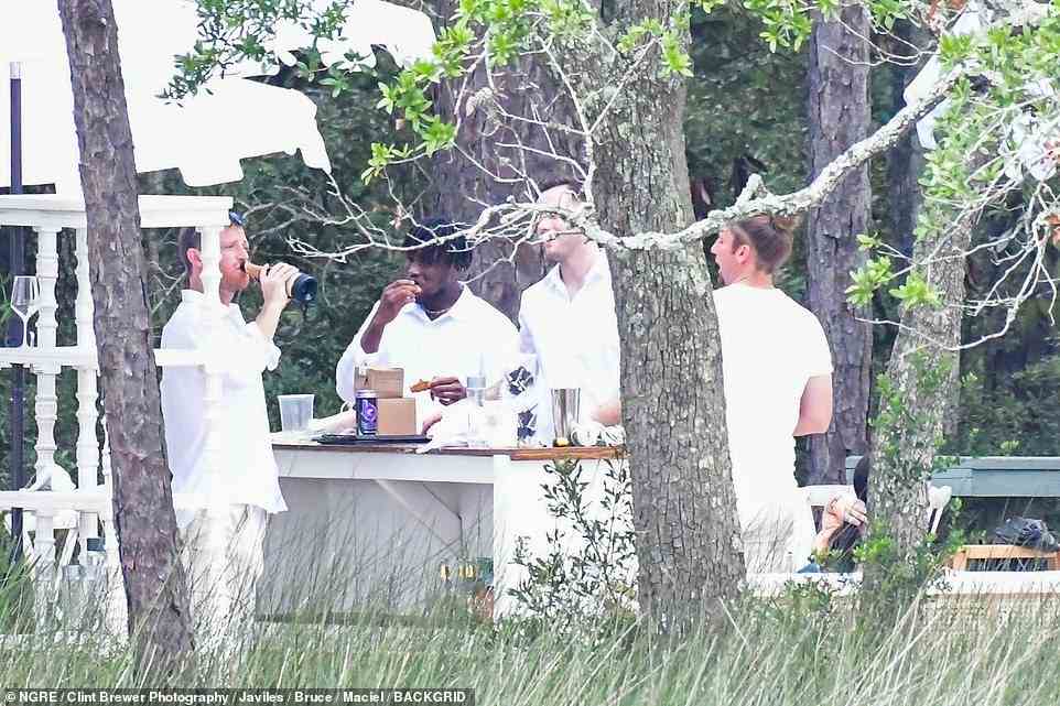 Die Männer waren ganz in Weiß abgebildet, als sie bei einem Grillfest nach der Hochzeit tranken und aßen