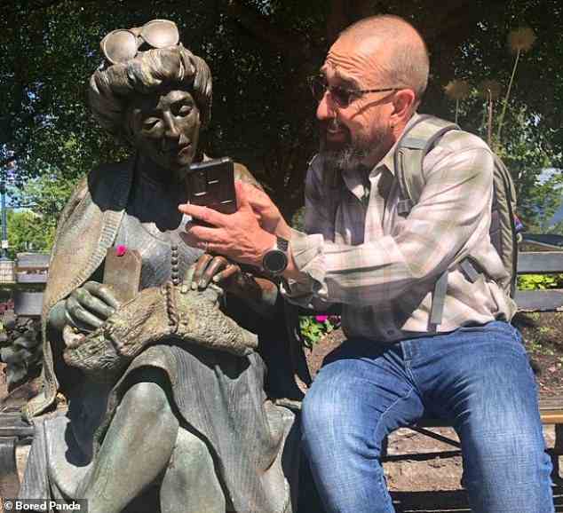 Oh was ist das?  Dieser Mann zeigt einer Metallfrau aufgeregt etwas Interessantes auf seinem Handy in Vancouver, Kanada
