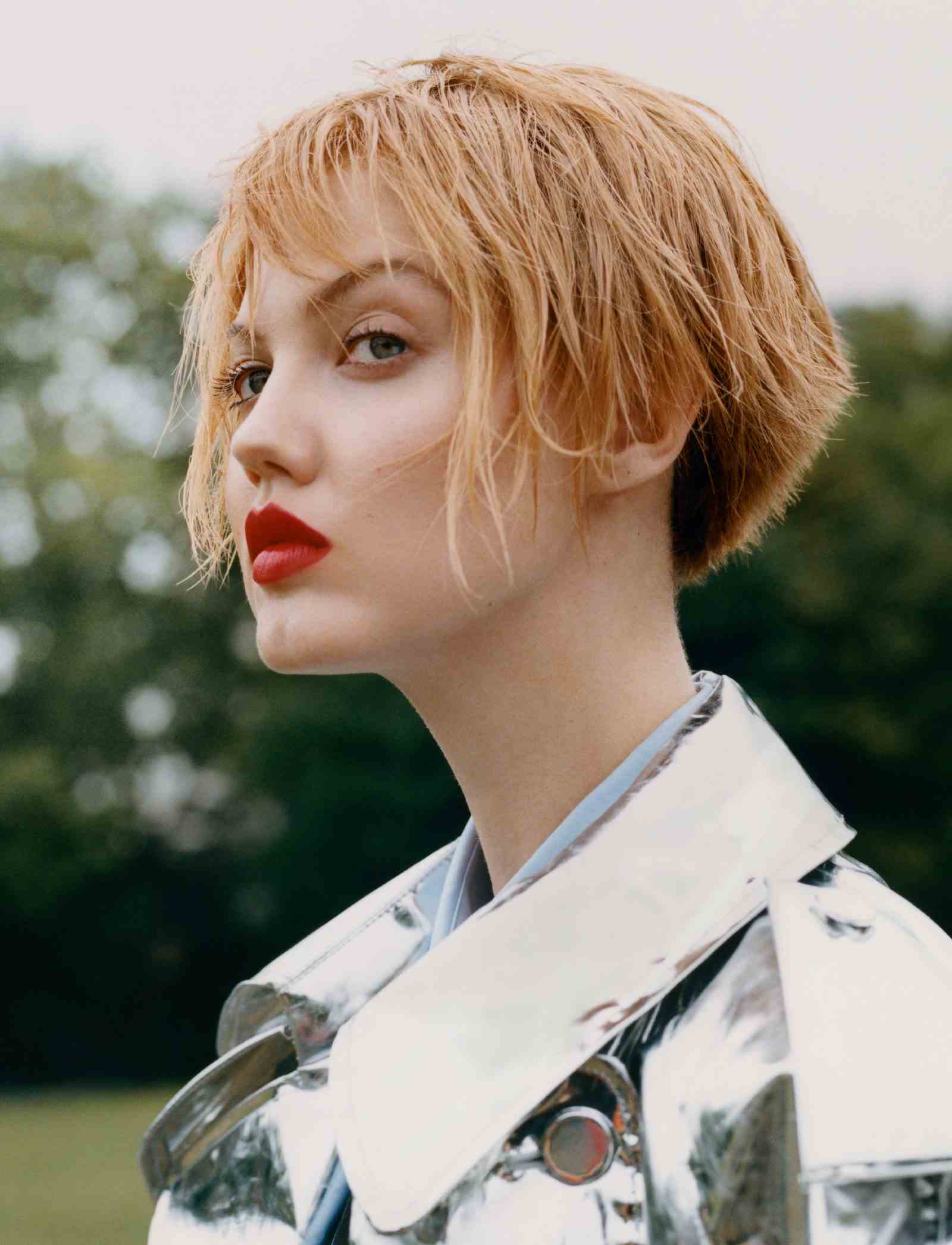 Nahaufnahme von Model Lindsey Wixson mit cremefarbenen roten Haaren, während sie draußen eine silberne Lederjacke trägt.
