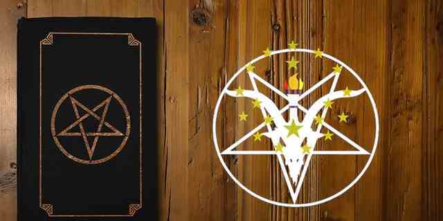Nahaufnahme auf einem schwarzen Buch mit einem vergoldeten umgekehrten Pentagramm auf einem braunen Holzbrett.