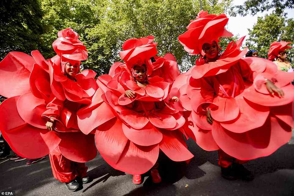 Children in bright red costumes, intricately made to resemble roses, perform at the parade