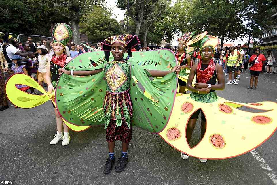Young children get ready to dance together through the streets of London in green, yellow and red