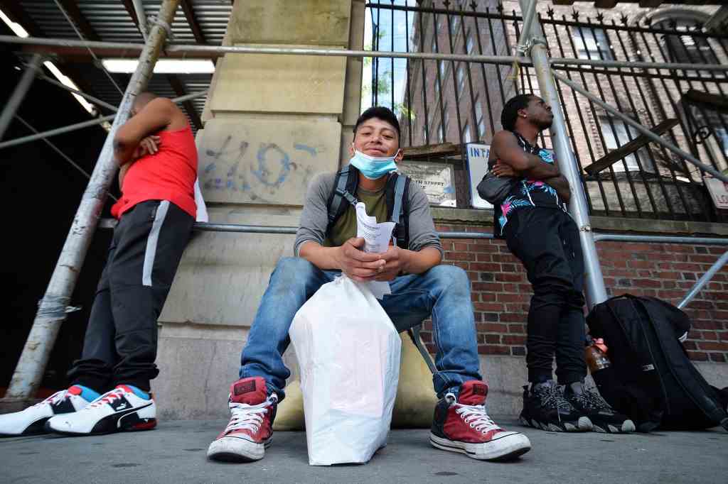 Migranten warten darauf, in einen Bus verladen zu werden, um am 11. August in eine Notunterkunft in Brooklyn gebracht zu werden.
