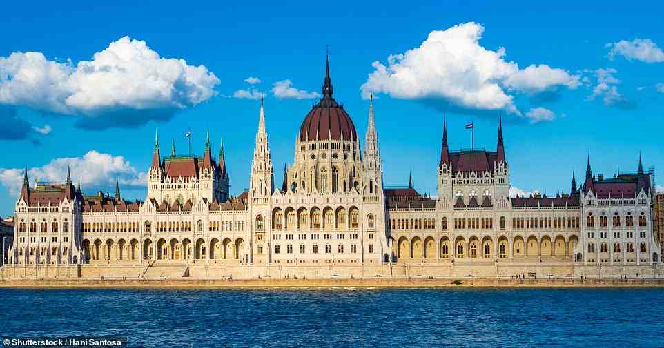 Von den Ufern der Donau aus färben sich die honigfarbenen Steine ​​des großen ungarischen Parlamentsgebäudes orange und dann rosa, wenn die Nacht hereinbricht