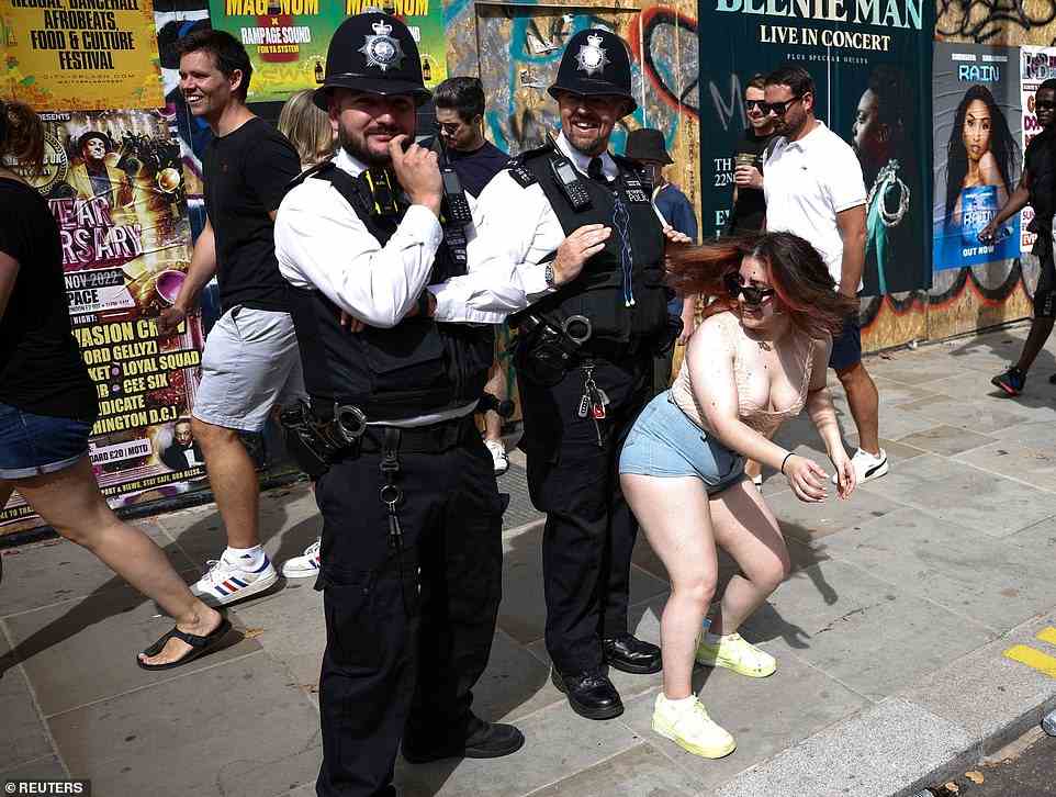 A reveller dances next to a police officer at Notting Hill Carnival in London today