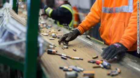 Mitarbeiter sortieren Batterien, die sich in einer Recyclinganlage auf einem Förderband bewegen.